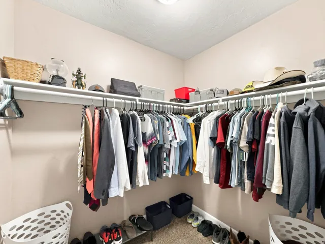Walk-in closet featuring extensive built-in shelving and hanging rods