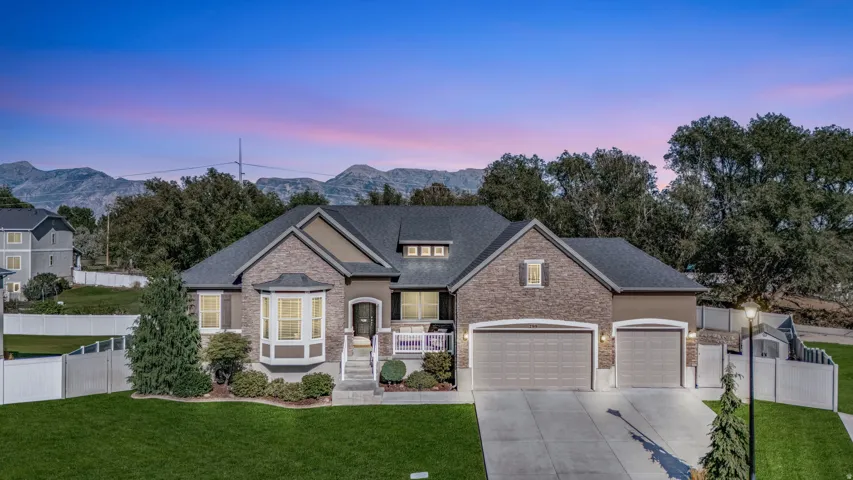 Brick and stucco exterior, prominent bay window, attached two-car garage, concrete driveway, and a mountain backdrop