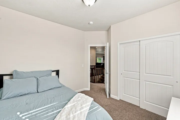 Carpeted room with neutral wall tones, white sliding closet doors with arch and panel details, and a ceiling-mounted light fixture