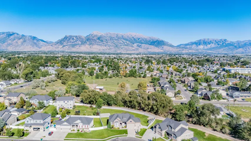 Expansive neighborhood with diverse residential architecture and mature trees, featuring distant mountain ranges under a clear sky