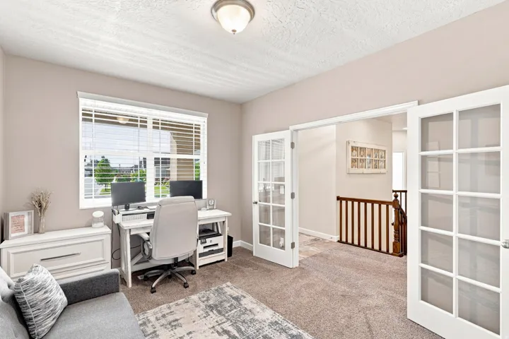 Carpeted room featuring a large window with blinds, a flush mount ceiling light, and white French doors