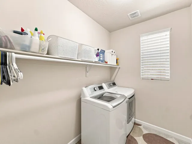 Laundry area featuring a mounted shelf, hanging rod, and a window with blinds