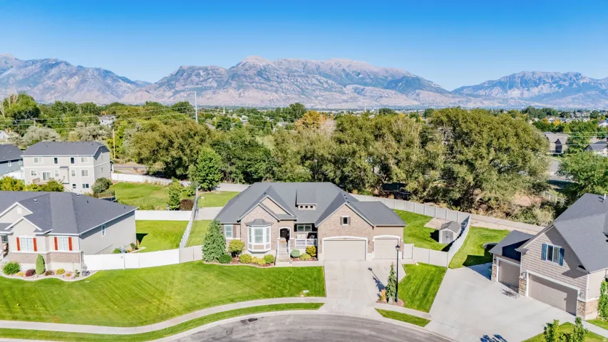 Brick and siding exterior with a two-car garage, mature landscaping, and an expansive lawn