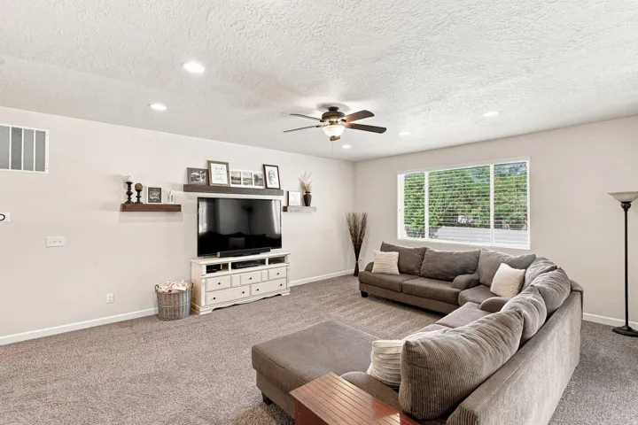 Recessed ceiling lighting, ceiling fan, carpeted flooring, built-in wall shelving, and expansive window