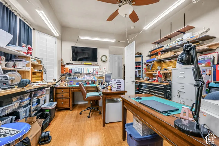 Wood-finish flooring, ceiling fan with light fixture, recessed fluorescent lighting, multiple built-in shelving units, and interior door