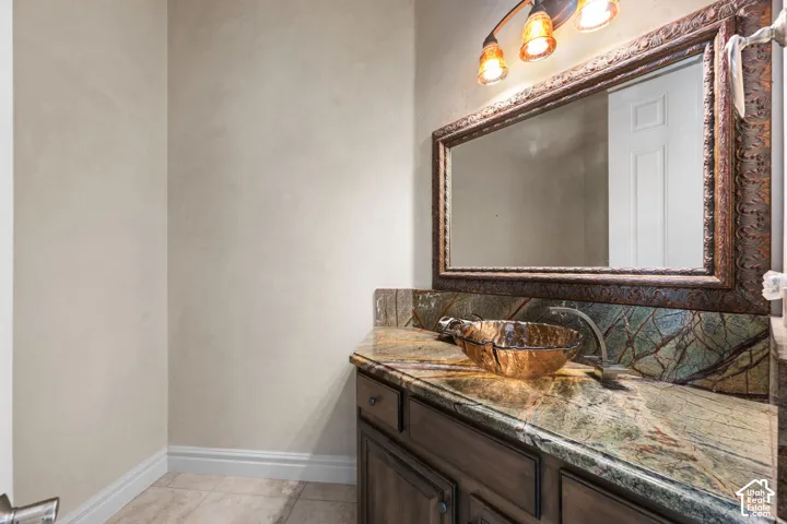 Custom vanity with a vessel sink, patterned countertop, and an ornate framed mirror