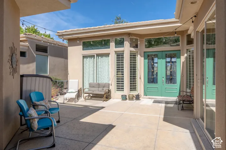 Expansive concrete patio with stucco exterior, double panel doors, vertical window panels, and integrated spa
