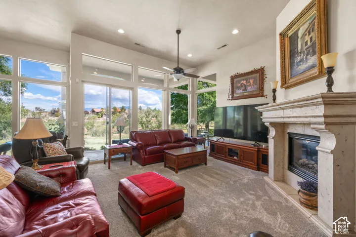 Stone-finish fireplace surround, recessed lighting, ceiling fan, expansive windows, and a sliding glass door