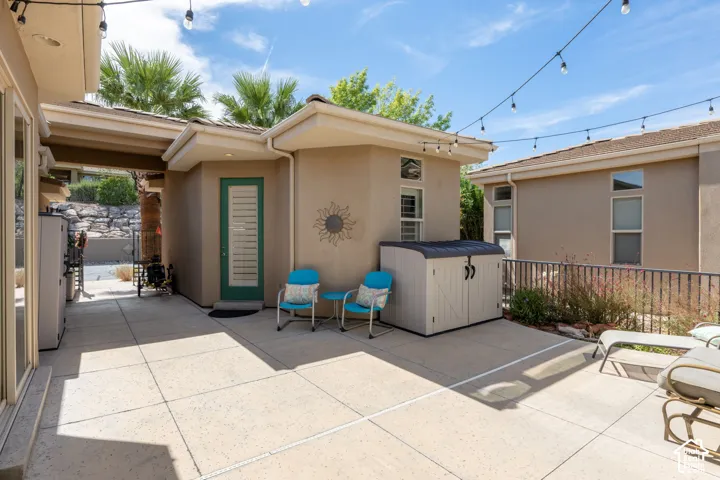 Expansive concrete patio with stucco exterior, recessed lighting, and a slatted door