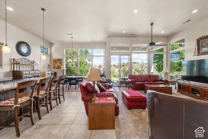 Open-concept living area with extensive windows, tile flooring, and a ceiling fan