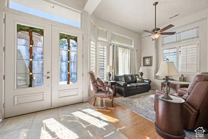 Double entry doors with decorative glass panels, transom windows, ceramic tile flooring, wood-finish flooring, and a ceiling fan with light fixture