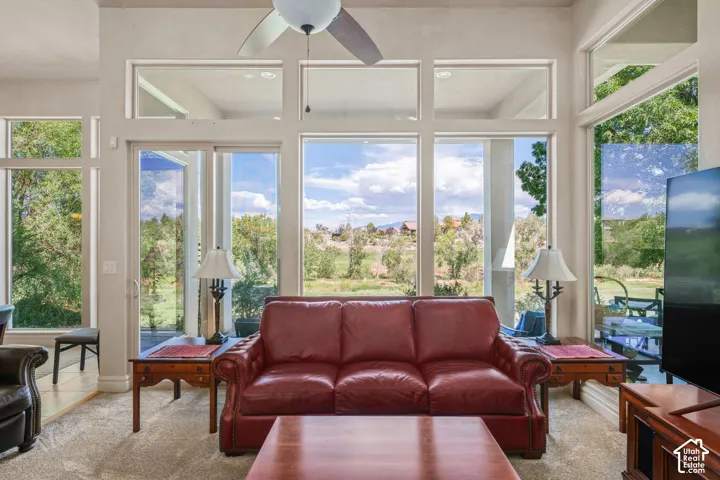 Expansive windows, glass patio doors, high ceilings, ceiling fan, and plush carpeting