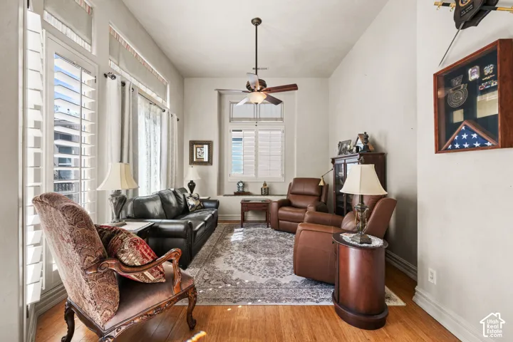 Vaulted ceiling with a ceiling fan, hardwood flooring, and window shutters