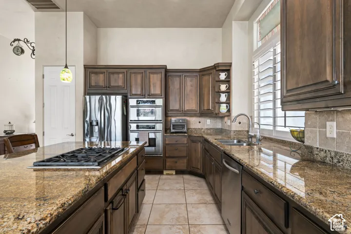 Kitchen featuring wood-finish cabinetry, stone slab countertops, stainless steel appliances, and a gas cooktop