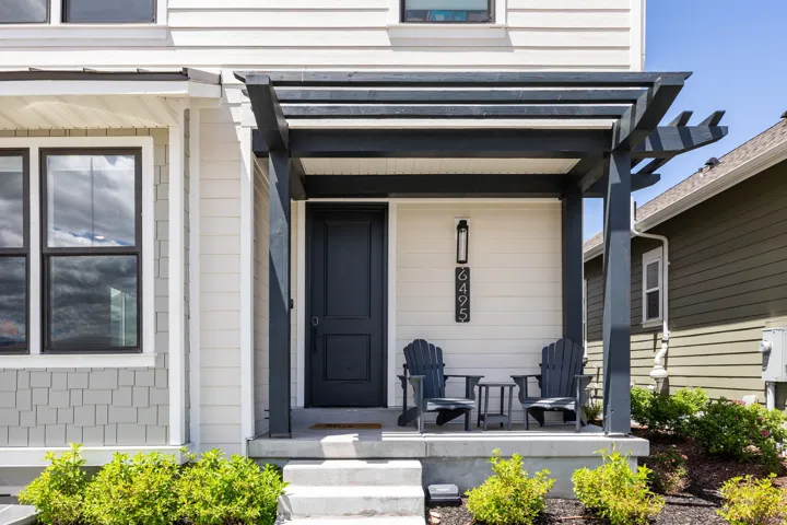 Front porch with a dark pergola, concrete steps, and a dark entry door