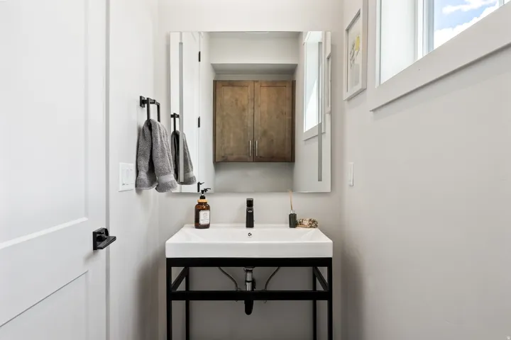 White floating vanity with a rectangular basin, matte black faucet, and coordinating black towel rack