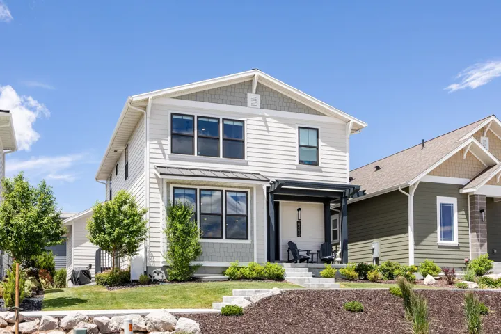 Modern two-story exterior featuring a covered entry, decorative pergola, and contrasting siding materials
