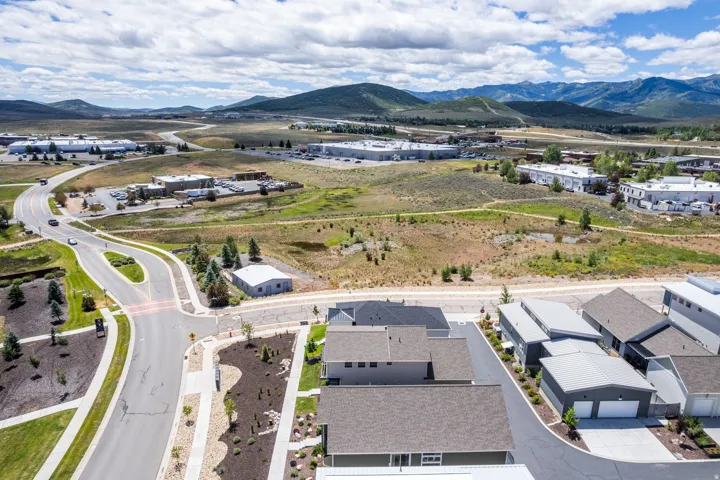 Mountainous terrain surrounds a developed area featuring residential and commercial structures, paved roads, and natural landscaping