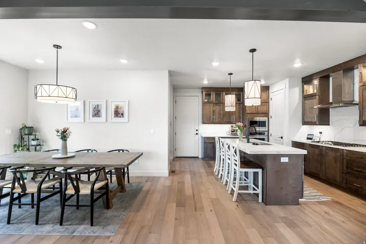 Open-concept living space with light wood-finish flooring, recessed lighting, and a kitchen featuring dark wood cabinetry and a central island with countertop seating