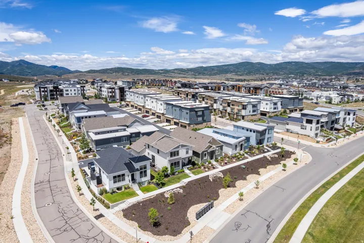 Modern residential development featuring a variety of architectural styles, streetscapes with sidewalks, and a mountainous backdrop