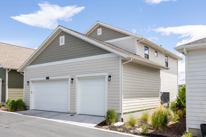 Two-car garage with white doors, exterior lighting fixtures, and light-colored siding