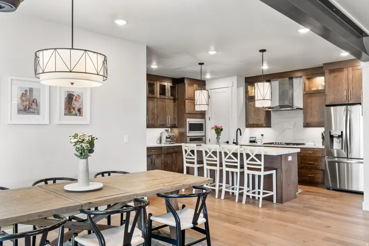 Hardwood flooring, island kitchen with integrated seating, stainless steel appliances, modern pendant lighting, and recessed ceiling lights