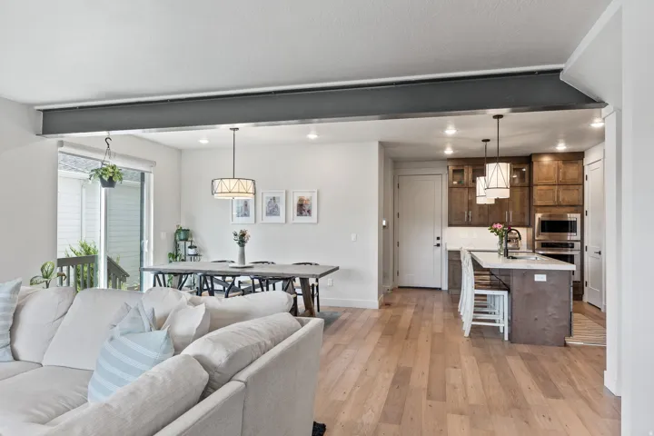 Open concept living area featuring wood-finish flooring, recessed lighting, and a kitchen with dark wood cabinetry and integrated appliances