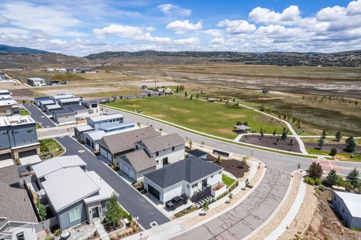 Modern residential area featuring a green space with walking paths and mountain scenery
