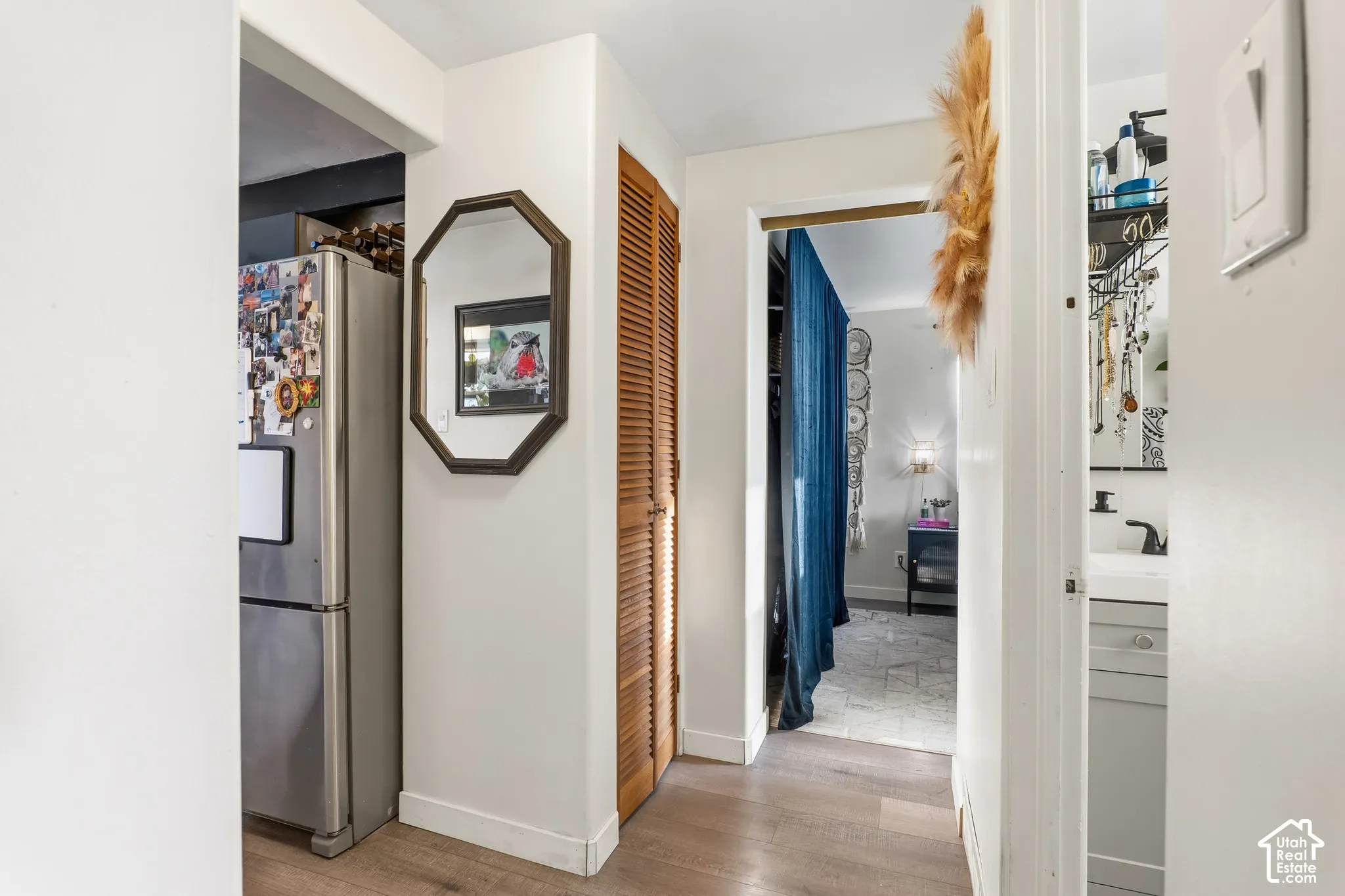 Wood-finish flooring throughout, featuring a louvered bifold door and an octagonal wall mirror