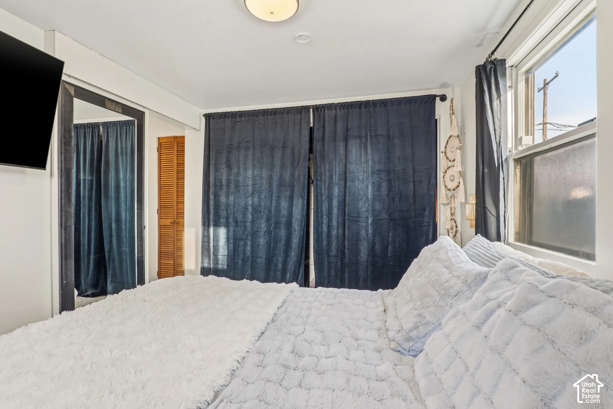 Recessed lighting, wood-finish bi-fold doors, and a window with dark privacy drapes