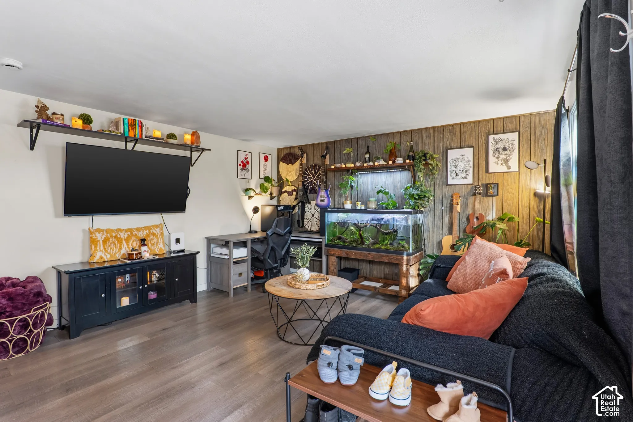 Spacious room featuring wood-finish flooring, a wood-paneled accent wall, and built-in shelving