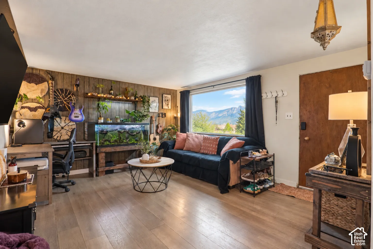 This photos was altered to show the new window, originally this photo showed a stained glass window that has been replaced. Hardwood-style flooring, a large picture window, and wood-paneled accent wall