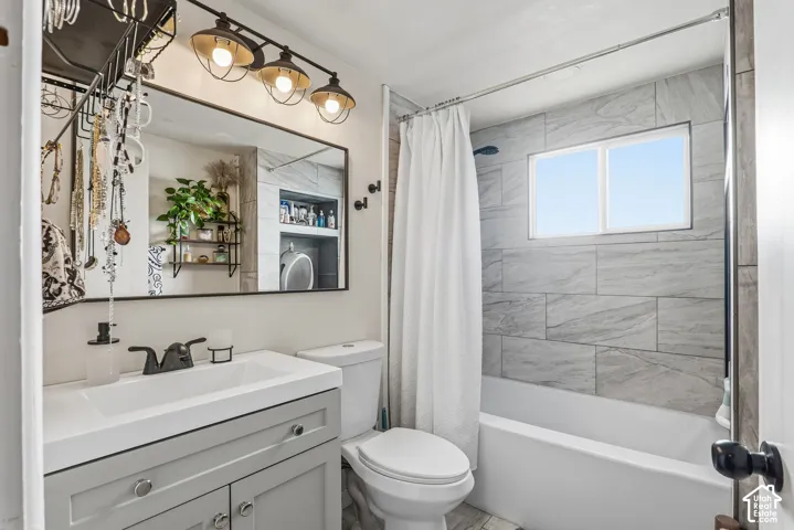 Vanity with a rectangular sink and matte black faucet, framed mirror, modern overhead lighting, tiled shower surround, and built-in window