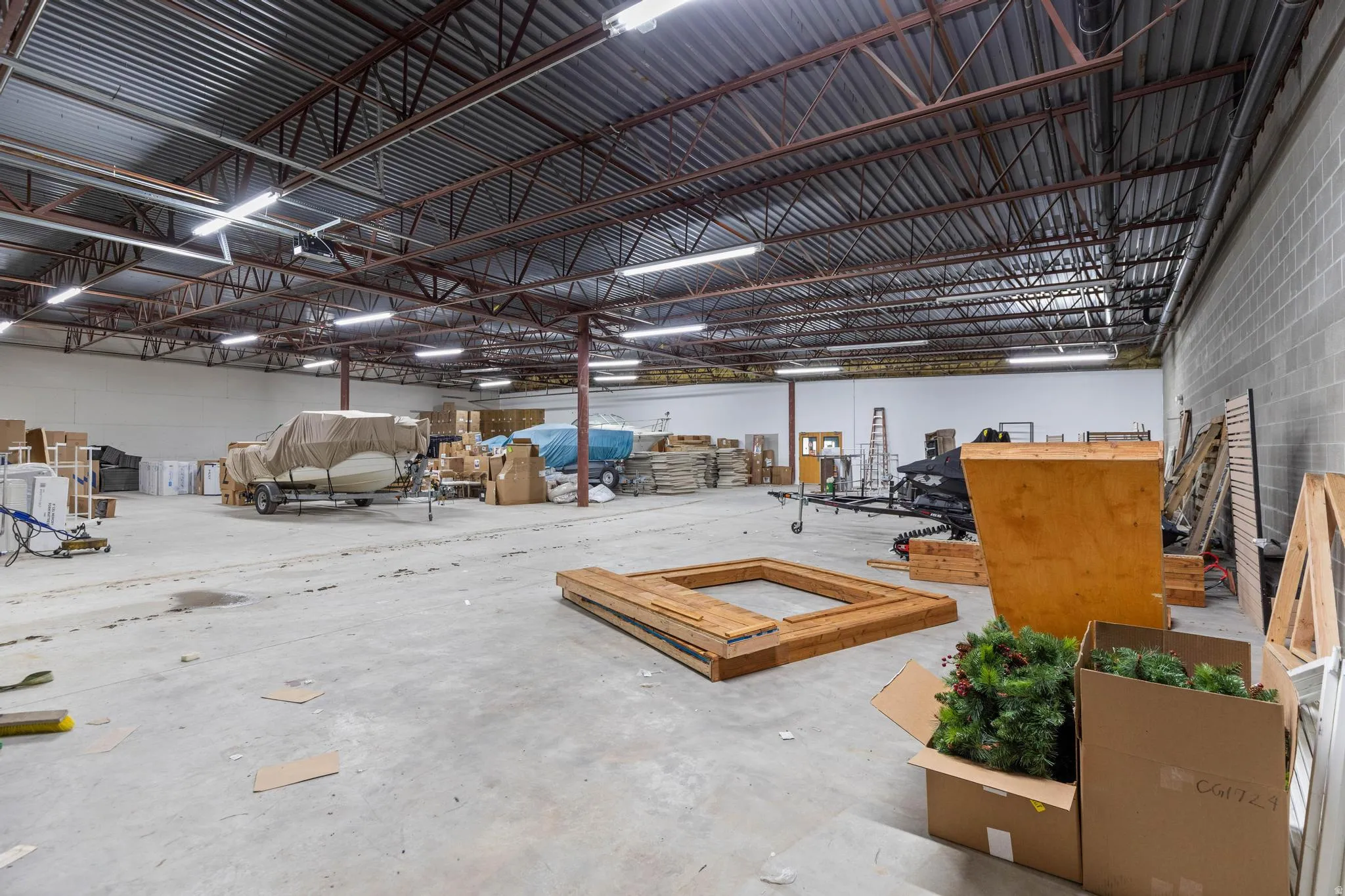 Spacious interior featuring a concrete floor, exposed metal ceiling joists, and fluorescent lighting