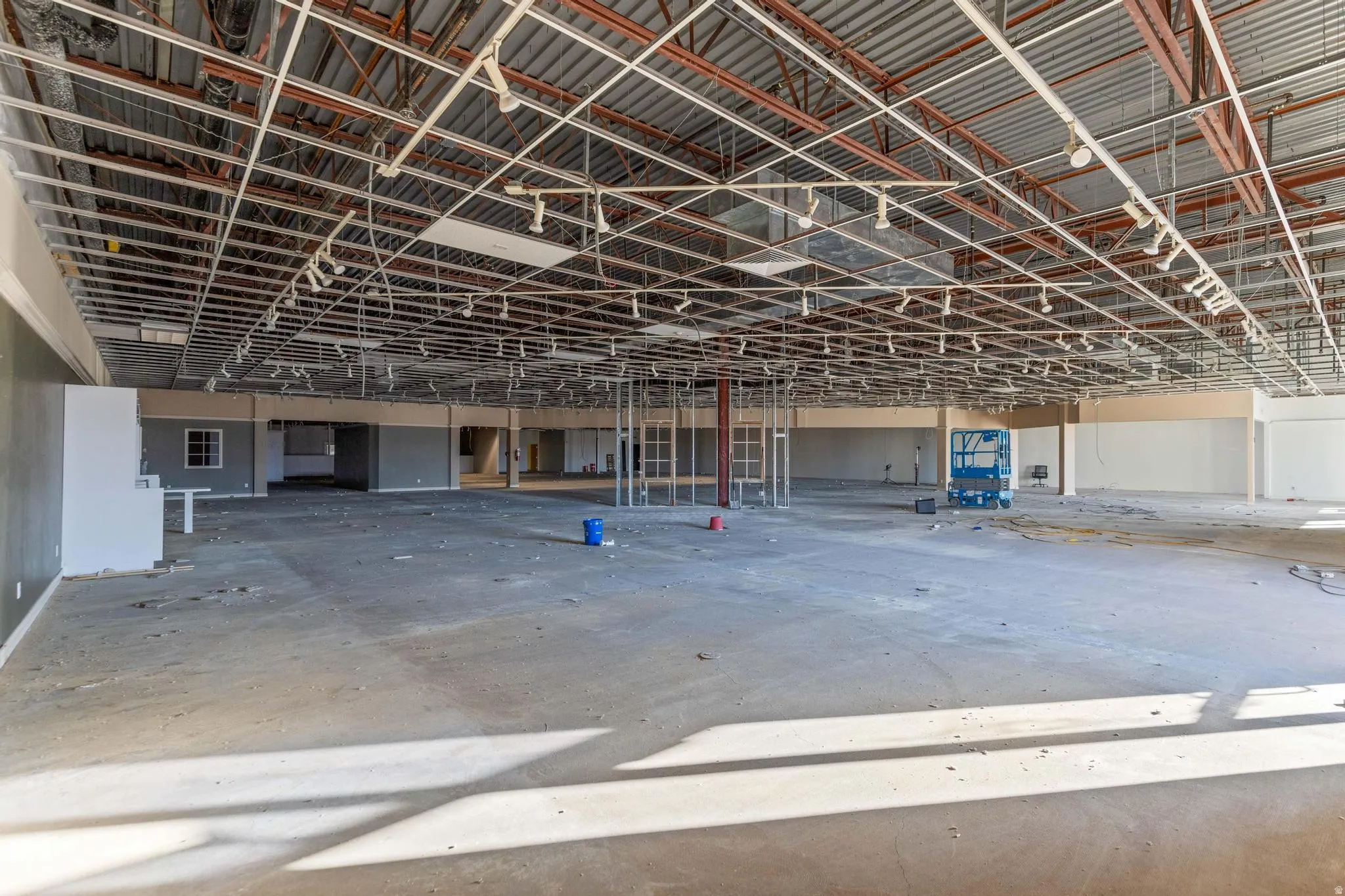 Open-concept commercial space featuring exposed ceiling infrastructure, concrete flooring, and track lighting