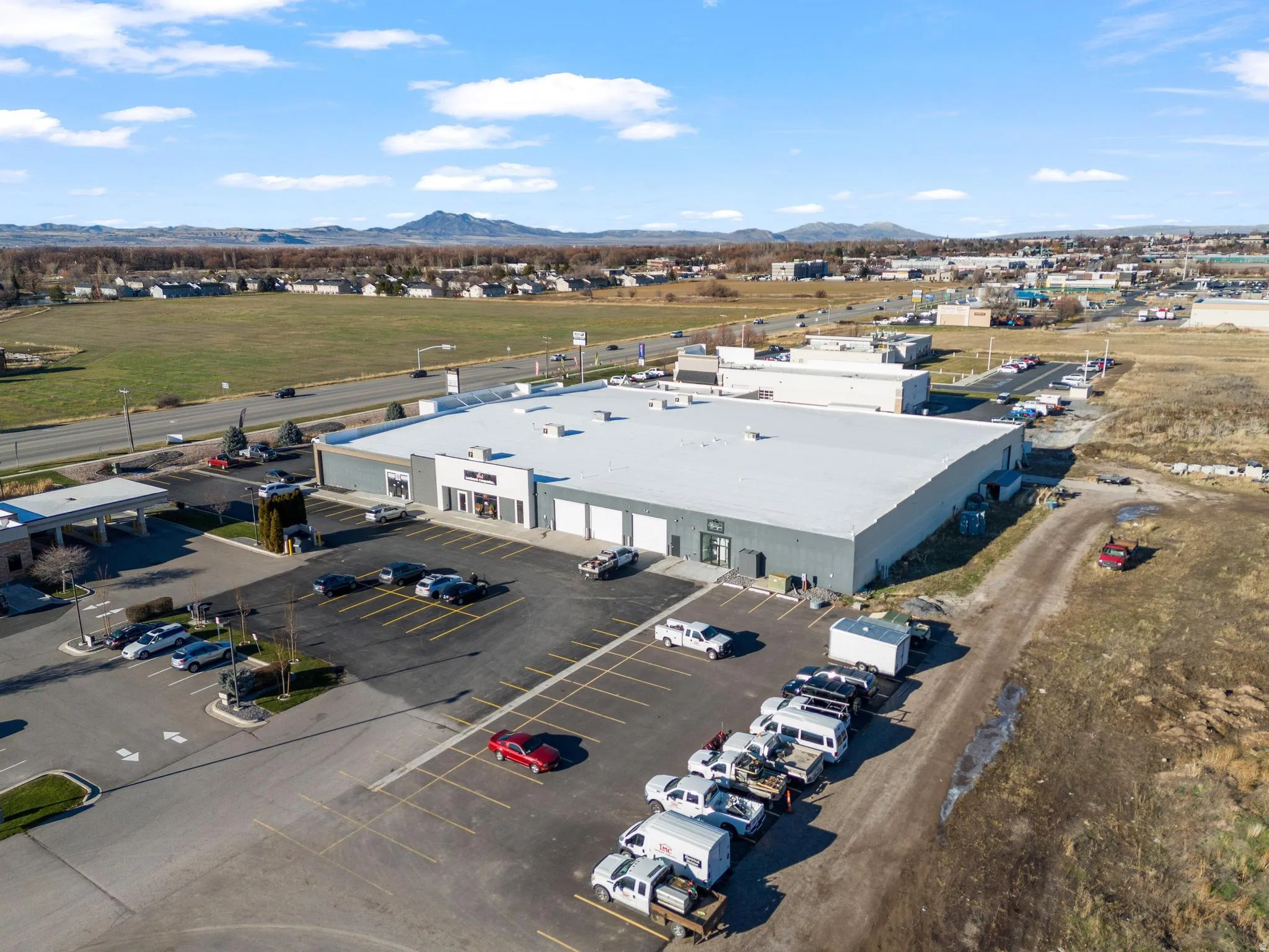 Commercial building featuring a large paved parking lot, multiple garage doors, and a flat roof