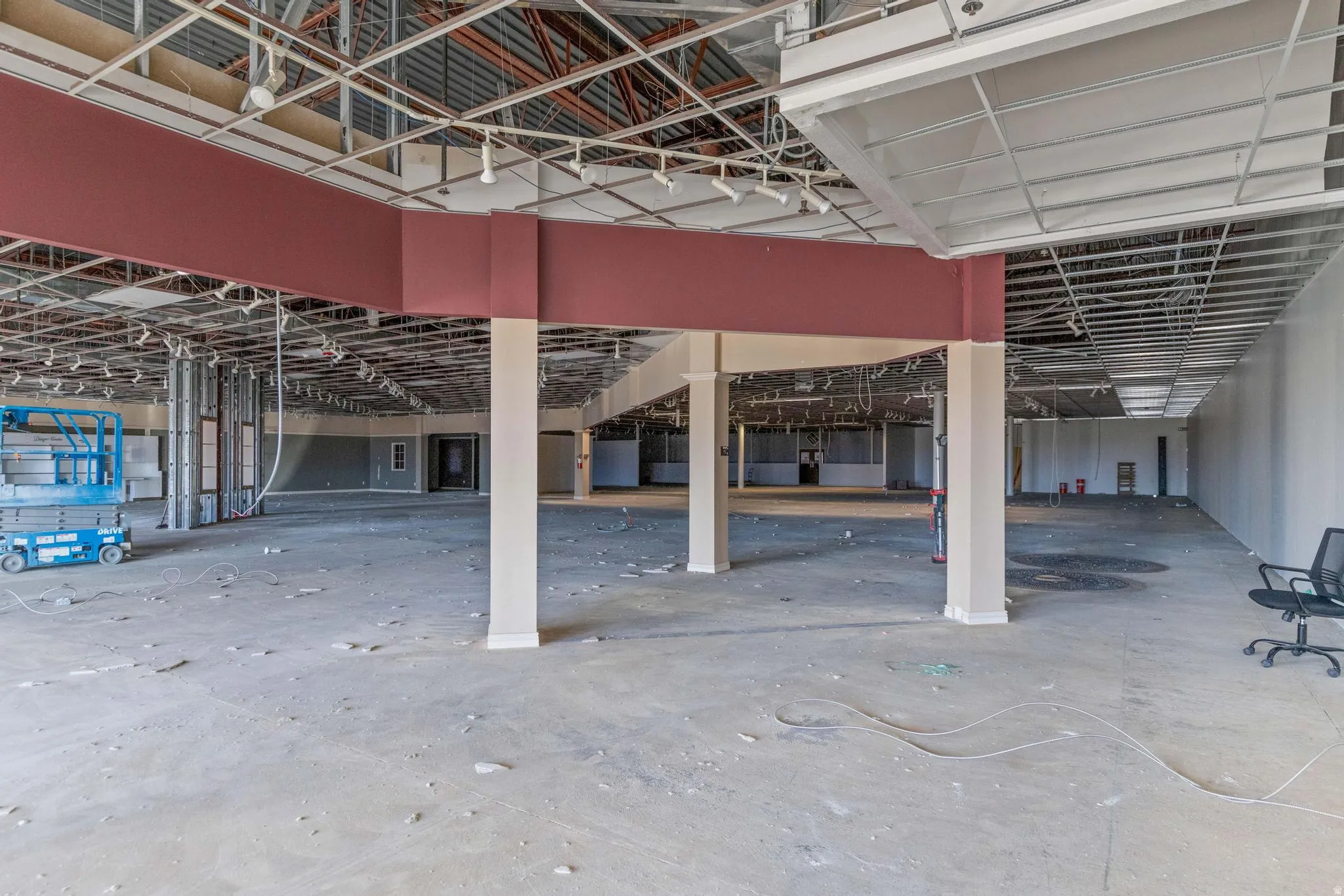 Expansive open floor plan with concrete flooring, suspended ceiling grid, and support columns