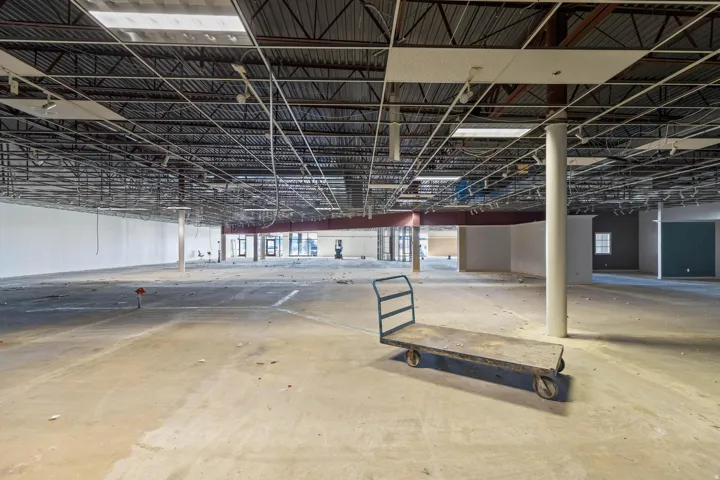 Expansive commercial space featuring high ceilings with exposed structural elements, concrete flooring, and multiple columns