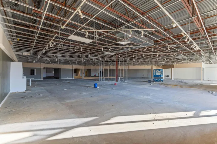 Open-concept commercial space featuring exposed ceiling infrastructure, concrete flooring, and track lighting