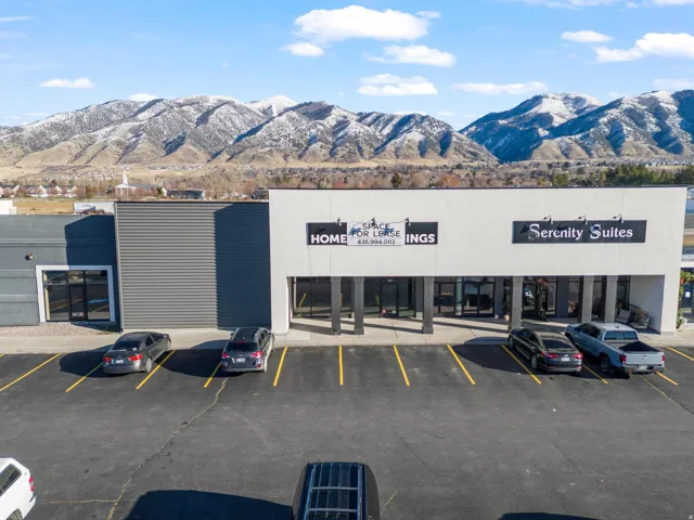 Commercial storefront with expansive glass entrances and a paved parking area