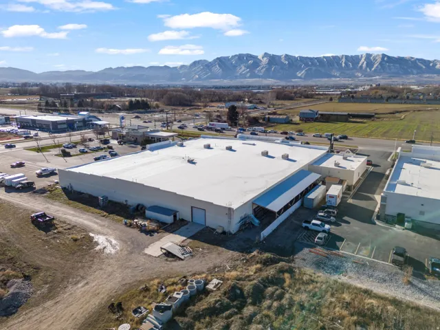 Industrial building featuring a white flat roof, multiple large bay doors, and extensive surrounding paved areas