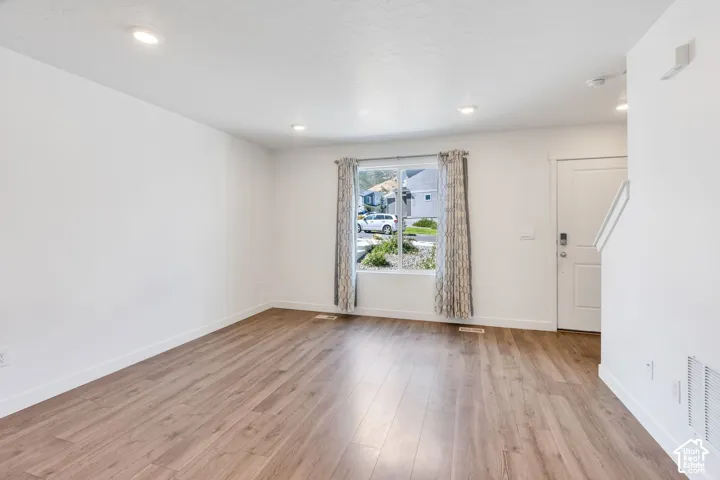 Bright interior with recessed lighting, wood-finish flooring, and a white entry door