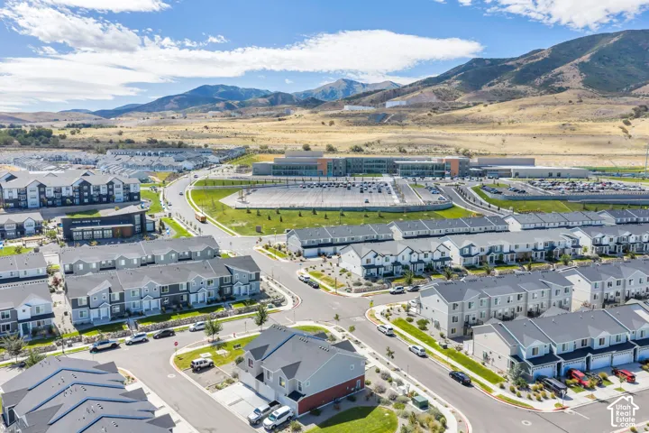 Modern residential community featuring multi-story townhomes and apartment buildings, surrounded by paved roads and manicured landscaping