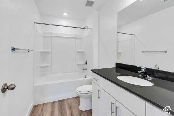 Bathroom featuring a white vanity with a dark countertop, an integrated sink, and white cabinetry