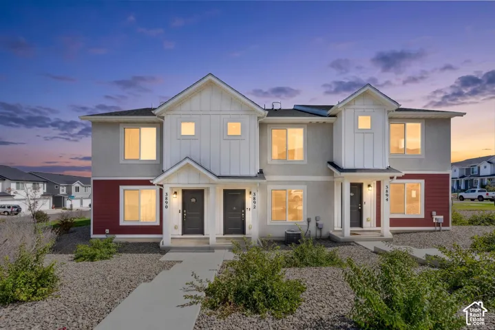 Contemporary townhome facade featuring a prominent gable, contrasting white board-and-batten siding, red horizontal siding, and grey stucco accents