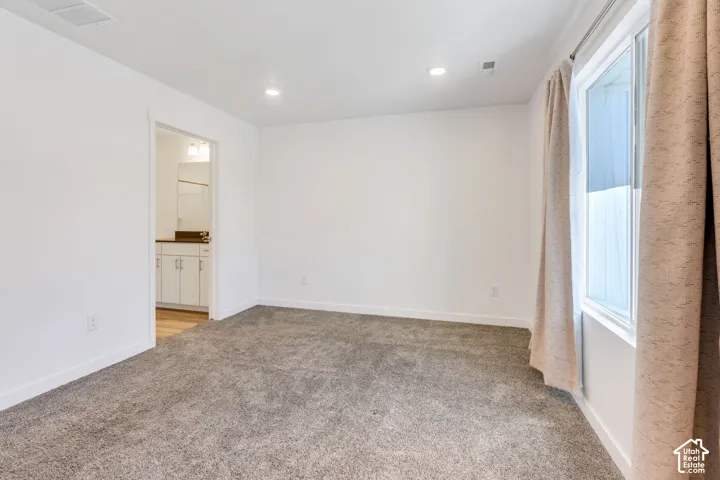 Recessed lighting, neutral wall paint, and gray carpeting