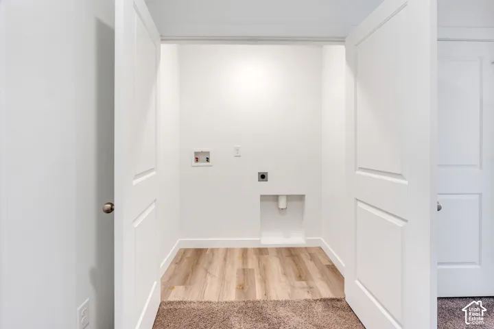 Recessed utility area with wood-finish flooring, bright white walls, and panel doors