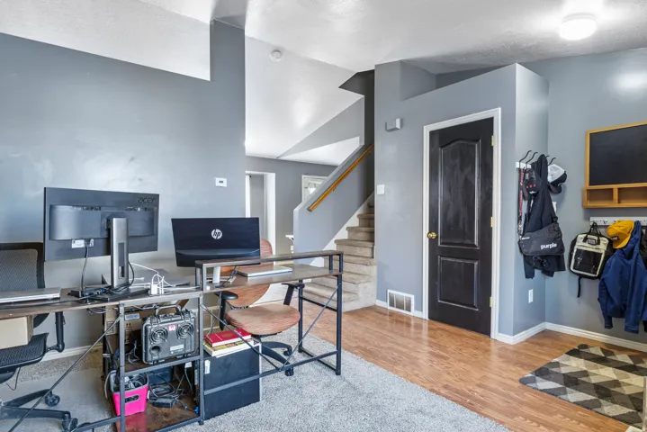 Wood-finish flooring, staircase with carpeted treads, built-in coat hooks, and an overhead lighting fixture