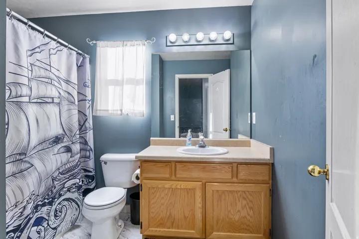 Vanity with a single basin sink, a light-toned countertop, and wood-finish cabinetry