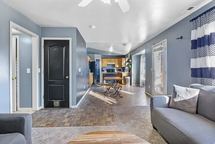 Open-concept living area featuring a ceiling fan, wood-finish flooring, and a glass-paneled exterior door